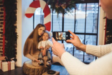 Tema Mobil fotoğraf, amatör fotoğraf ve video üstünde telefon. Ellerini beyaz adam kullanır smartphone anne ve oğlu evde fotoğraf Noel zaman Yılbaşı dekor içinde kışın pencere yapar tutar.