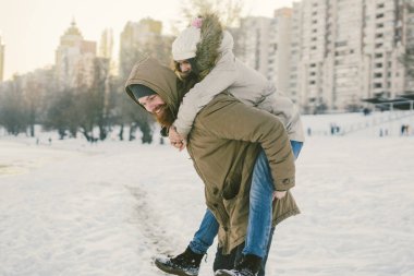 Tema yeni yıl Noel ruh kış kar Tatil Sevgililer günü. Kafkas çift aşıklar neşe, kahkaha Şehir Parkı suya kandırmak. adam kadının omuzlarında sırt çantası tutar.