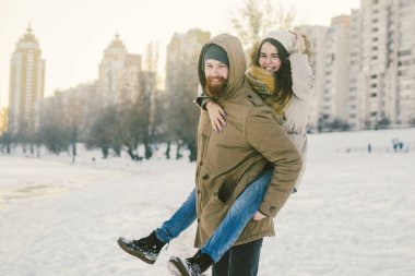Tema yeni yıl Noel ruh kış kar Tatil Sevgililer günü. Kafkas çift aşıklar neşe, kahkaha Şehir Parkı suya kandırmak. adam kadının omuzlarında sırt çantası tutar.
