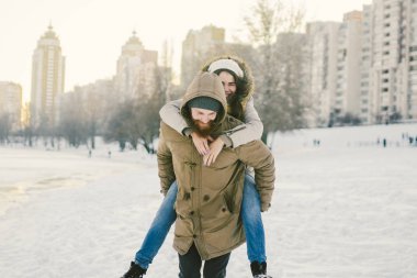 Tema yeni yıl Noel ruh kış kar Tatil Sevgililer günü. Kafkas çift aşıklar neşe, kahkaha Şehir Parkı suya kandırmak. adam kadının omuzlarında sırt çantası tutar.