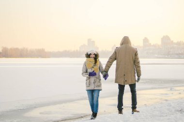 Tema Noel tatil kış yeni yıl. Seven çift genç şık beyaz donmuş bir gölün kıyısında yürüyüş Heteresexual. Tarih. Sevgililer günü gün batımında kışın. Aşk ve romantizm Tema.