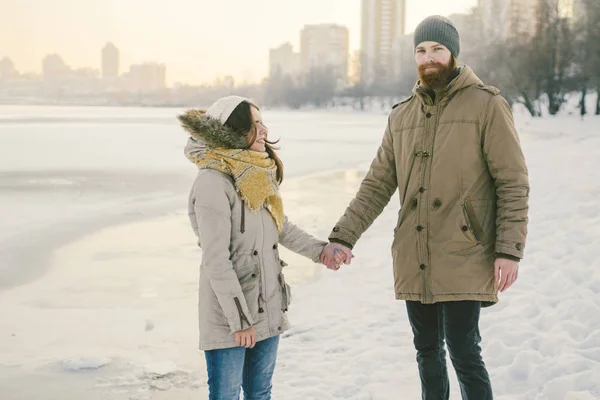 Theme Christmas holidays winter new year. Young stylish Caucasian loving couple Heteresexual walking on the shore of a frozen lake. Date. Valentines Day in winter at sunset. Love and Romance Theme.