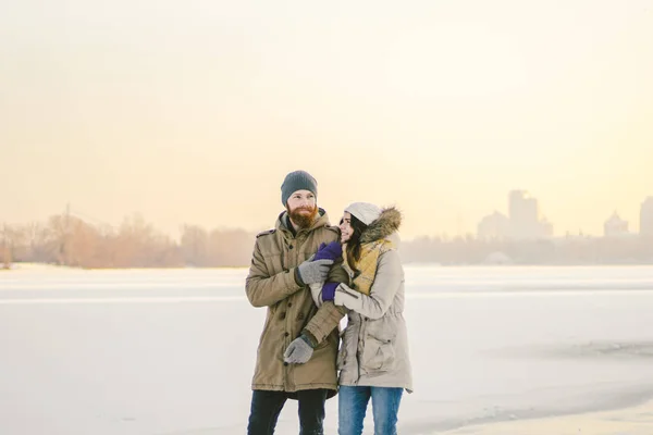 主题圣诞节假期冬季新年 年轻的时尚的白种人爱的夫妇异性行走在一个冰冻的岸边 情人节在冬天在日落 爱情与浪漫主题 — 图库照片