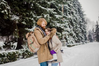 Güzel genç beyaz insanlar aşık bir tarihte kış Park'ta bir çift gördüm. Bir adam bir sakal, paten ve bir sırt çantası ile hugs, bir adam, bir kadın bir tarih Sevgililer günü doğada seviyor.