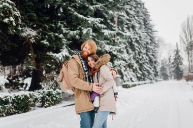 Güzel genç beyaz insanlar aşık bir tarihte kış Park'ta bir çift gördüm. Bir adam bir sakal, paten ve bir sırt çantası ile hugs, bir adam, bir kadın bir tarih Sevgililer günü doğada seviyor.