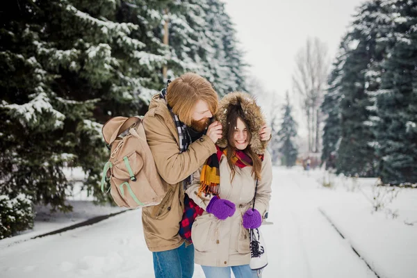 美丽的年轻白种人夫妇情侣在冬季公园的约会 一个有胡子 溜冰鞋 背包拥抱的男人 一个男人爱一个女人 一个在大自然中的情人节约会 — 图库照片