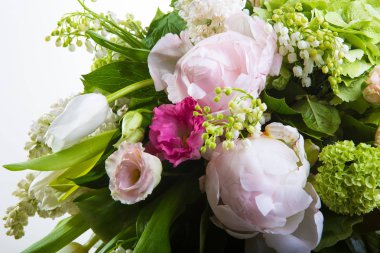 Çok sayıda yety, kardelen, gül, çan ve şakayık beyaz bir bacak üzerinde bir büyük uzun şık şeffaf cam aranjman yeşillikleri ile bir büyük yemyeşil buket arka plan izole.