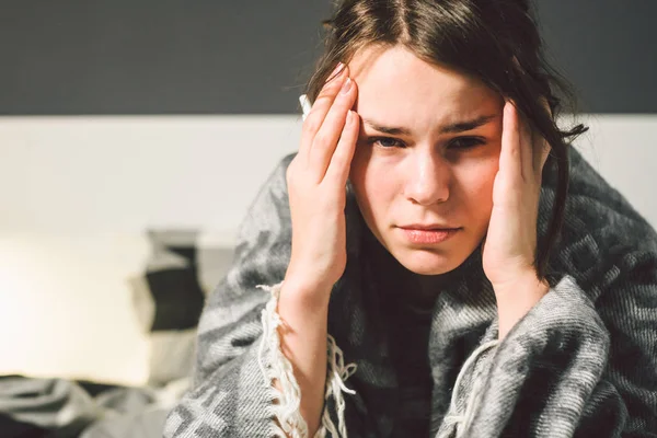 Sujeto enfermedad y tratamiento. joven mujer caucásica se sienta en casa dormitorio cama envuelta en manta corporal con fiebre alta, fiebre sostiene fuerte dolor de cabeza detrás de la cabeza, utiliza medicamentos de gota en la nariz para la sinusitis — Foto de Stock