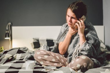 respiratory diseases and home remedies. young woman sick with cold sitting bedroom on bed holding throat sadness emotion. Sore throat man takes pills. Call phone, ask for help doctor. Call ambulance.