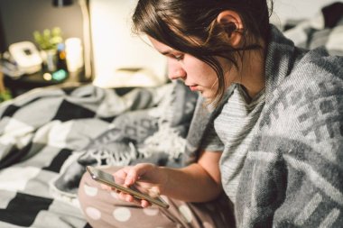 Konu hastalık ve teknoloji. Cep telefonu arama bilgileri, Internet üzerinden satın ilaçlar online bağlantılarıyla Doktor, sosyal ağlar ev yatak odasında genç beyaz bir kadın kullanır.