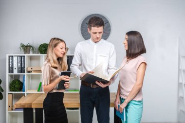 Tema işletme, ekip çalışması ve ortaklıklar. Bir grup genç insan, üç kişi, resmi kıyafet tablosunda yakın bir ofiste durmak, belgelerle çalışmak, praks işaret sözleşme yapmak.