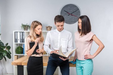 Tema işletme, ekip çalışması ve ortaklıklar. Bir grup genç insan, üç kişi, resmi kıyafet tablosunda yakın bir ofiste durmak, belgelerle çalışmak, praks işaret sözleşme yapmak.