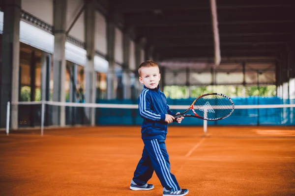 2016 ウクライナ Kiev Theme の物理的な開発の子供たち 白人の子少年 年間テニス ラケット ボールで古いポーズ手テニス オレンジ樹皮背景 — ストック写真