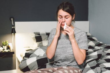 Mevsimlik soğuk, burun akıntısı grip virüsü enfeksiyonu temasıdır. Ev yatak odası yatak Genç beyaz kadına ilaç sprey damla burnuna sümük için kullanır. Alerjik renitis ve sinüzit.