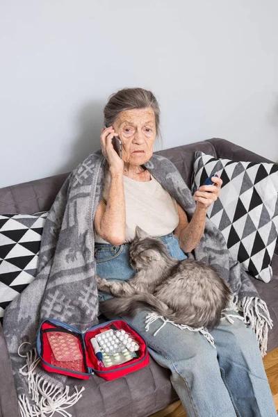 主题老人和糖尿病 年龄较大的白种人妇女与灰毛皱纹回家在沙发上测量血糖水平血液与帮助医疗设备使用血糖仪 手耳电话救护车 — 图库照片