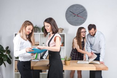 Konu iş, takım çalışması ve müzakerelerin ofiste. 4 beyaz insanlar odasında belgelerle çalışma grubu. İki genç kadın patron şirket çalışanları fonunda poz.