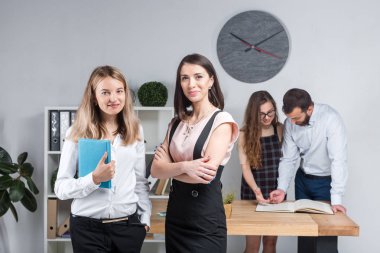 Konu iş, takım çalışması ve müzakerelerin ofiste. 4 beyaz insanlar odasında belgelerle çalışma grubu. İki genç kadın patron şirket çalışanları fonunda poz.