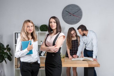 Konu iş, takım çalışması ve müzakerelerin ofiste. 4 beyaz insanlar odasında belgelerle çalışma grubu. İki genç kadın patron şirket çalışanları fonunda poz.