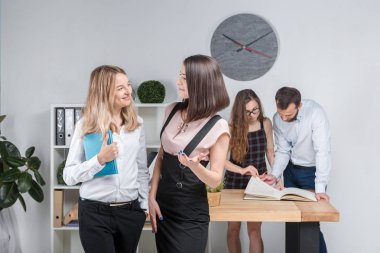 Konu iş, takım çalışması ve müzakerelerin ofiste. 4 beyaz insanlar odasında belgelerle çalışma grubu. İki genç kadın patron şirket çalışanları fonunda poz.