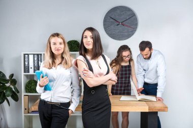 Konu iş, takım çalışması ve müzakerelerin ofiste. 4 beyaz insanlar odasında belgelerle çalışma grubu. İki genç kadın patron şirket çalışanları fonunda poz.