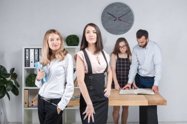 Konu iş, takım çalışması ve müzakerelerin ofiste. 4 beyaz insanlar odasında belgelerle çalışma grubu. İki genç kadın patron şirket çalışanları fonunda poz.