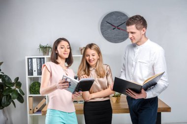 Tema işletme, ekip çalışması ve ortaklıklar. Bir grup genç insan, üç kişi, resmi kıyafet tablosunda yakın bir ofiste durmak, belgelerle çalışmak, praks işaret sözleşme yapmak.