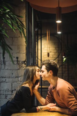 Tema aşk ve tatil Sevgililer günü. Üniversite öğrencileri birlikte beyaz heteroseksüel severler kış kafe içinde birkaç boş tablo kucaklama otur. Duygu mutluluk ve sevgi.