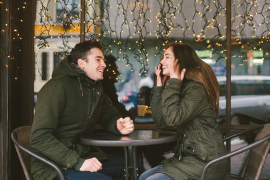 Tema aşk Tatil Sevgililer günü. Çift üniversite öğrencileri, kış, beyaz heteroseksüel severler arka plan pencere ışıklar karşı cadde kafe masaya oturabiliriz. Mutluluk ve sevgi duygu romantizm.