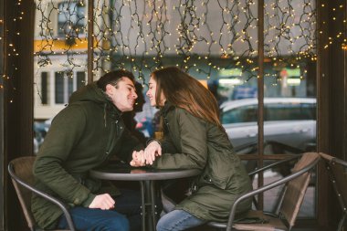 Tema aşk Tatil Sevgililer günü. Çift üniversite öğrencileri, kış, beyaz heteroseksüel severler arka plan pencere ışıklar karşı cadde kafe masaya oturabiliriz. Mutluluk ve sevgi duygu romantizm.