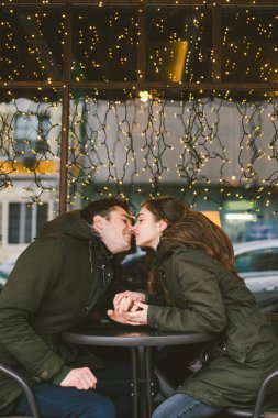 Tema aşk Tatil Sevgililer günü. Çift üniversite öğrencileri, kış, beyaz heteroseksüel severler arka plan pencere ışıklar karşı cadde kafe masaya oturabiliriz. Mutluluk ve sevgi duygu romantizm.