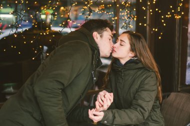 Tema aşk Tatil Sevgililer günü. Çift üniversite öğrencileri, kış, beyaz heteroseksüel severler arka plan pencere ışıklar karşı cadde kafe masaya oturabiliriz. Mutluluk ve sevgi duygu romantizm.