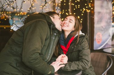 Tema aşk Tatil Sevgililer günü. Çift üniversite öğrencileri, kış, beyaz heteroseksüel severler arka plan pencere ışıklar karşı cadde kafe masaya oturabiliriz. Mutluluk ve sevgi duygu romantizm.