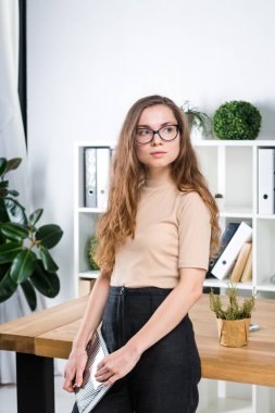 Bir office odada bir masa yakınındaki bir ofiste uzun saçlı ve gözlüklü sürtünme ile genç beyaz bir kadın portresi duruyor. Üniversite öğrencisi kız. Öğrenme konu adam.