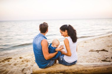 Tema Aile hafta sonu, plaj yaz tatili çocuk ile. Üç baba anne ve kızı genç şık aile yalancı ağaç sırtlarını ile bir yıl oturup, yaz aylarında bakan ufuk deniz günbatımı oturum.