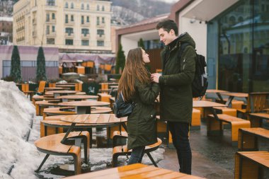 Aşk ve bir kız ve bir sokak teras kafe tablolar kucaklayan bir öğrenci stand genç bir çift boş insanlar olmadan kış için kapalı. Ölü sezon yemek Restoran kötü hava