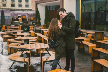 Aşk ve bir kız ve bir sokak teras kafe tablolar kucaklayan bir öğrenci stand genç bir çift boş insanlar olmadan kış için kapalı. Ölü sezon yemek Restoran kötü hava