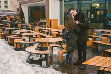 Aşk ve bir kız ve bir sokak teras kafe tablolar kucaklayan bir öğrenci stand genç bir çift boş insanlar olmadan kış için kapalı. Ölü sezon yemek Restoran kötü hava