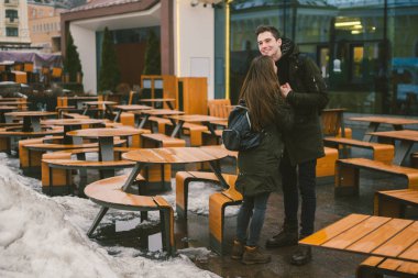 Aşk ve bir kız ve bir sokak teras kafe tablolar kucaklayan bir öğrenci stand genç bir çift boş insanlar olmadan kış için kapalı. Ölü sezon yemek Restoran kötü hava