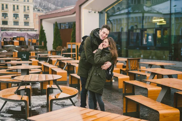 Влюблённая молодая пара и девушка и студенческий стенд, обнимающие столики уличного кафе на террасе, закрываются без людей на зиму. Вне сезона ресторан питания плохая погода — стоковое фото