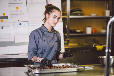 Konu meslek ve pişirme pasta. pasta şefi yuvarlak çikolata hazırlama Restoran mutfağında dövme olan beyaz kadın siyah eldiven ve üniforma içinde el yapımı truffle şekerler.