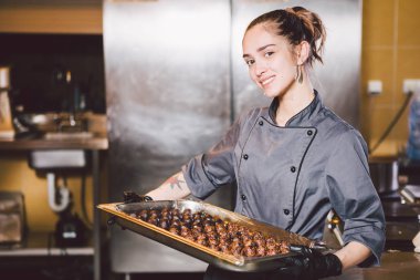 Konu meslek ve pişirme pasta. pasta şefi yuvarlak çikolata hazırlama Restoran mutfağında dövme olan beyaz kadın siyah eldiven ve üniforma içinde el yapımı truffle şekerler.