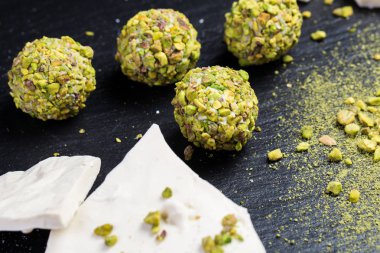 Tema şekerli tatlı pasta el yapımı. Makro yakın çekim tatlı tatlı tatlı şeker yuvarlak top beyaz trüf topu küme beyaz çikolata, matcha çay ve siyah bir zemin üzerine Antep fıstığı.