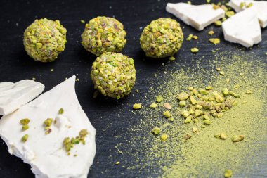 Tema şekerli tatlı pasta el yapımı. Makro yakın çekim tatlı tatlı tatlı şeker yuvarlak top beyaz trüf topu küme beyaz çikolata, matcha çay ve siyah bir zemin üzerine Antep fıstığı.