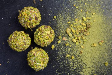 Tema şekerli tatlı pasta el yapımı. Makro yakın çekim tatlı tatlı tatlı şeker yuvarlak top beyaz trüf topu küme beyaz çikolata, matcha çay ve siyah bir zemin üzerine Antep fıstığı.