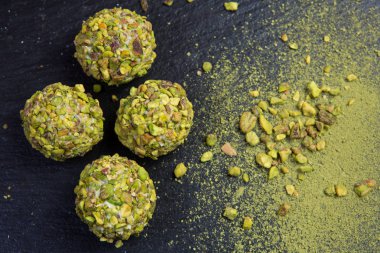 Tema şekerli tatlı pasta el yapımı. Makro yakın çekim tatlı tatlı tatlı şeker yuvarlak top beyaz trüf topu küme beyaz çikolata, matcha çay ve siyah bir zemin üzerine Antep fıstığı.