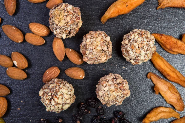 Theme is a sweet dessert made from natural products without sugar. Macro close up closeup dessert sweet candy round ball handmade truffle dried fruit set of almonds dried pear and honey.