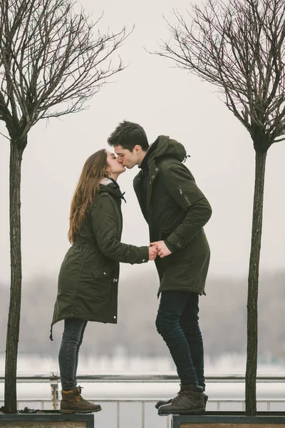 A heterosexual couple young people in love students a man and a Caucasian woman. In winter, in the city square covered with ice, they walk, hug and kiss. Love concept in any weather.