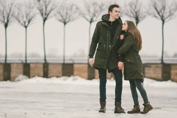 一对异性恋夫妇的年轻人在恋爱学生一个男人和一个白人妇女 在被冰覆盖的城市广场上 他们走着 拥抱着 亲吻着 爱的概念在任何天气 — 图库照片