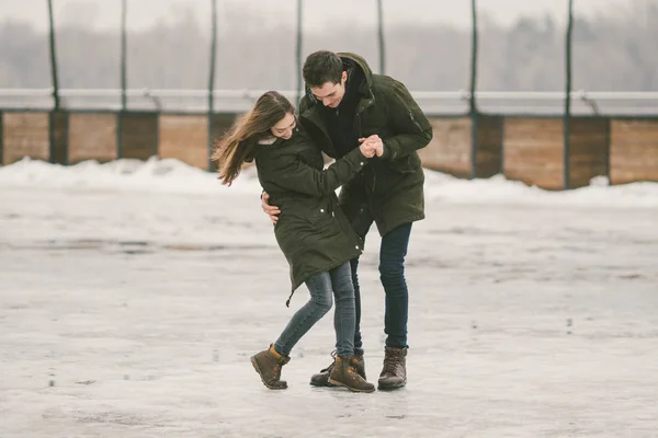 一对异性恋夫妇的年轻人在恋爱学生一个男人和一个白人妇女 在被冰覆盖的城市广场上 他们走着 拥抱着 亲吻着 爱的概念在任何天气 — 图库照片