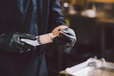 Tema yemek. Ellerini kapatın. Beyaz delikanlı mutfakta siyah üniforma ve lateks eldiven. Restoran kıyma hazırlar ve berry şırınga ile yol açar. İncir, incir veya Karya ficus çanak.